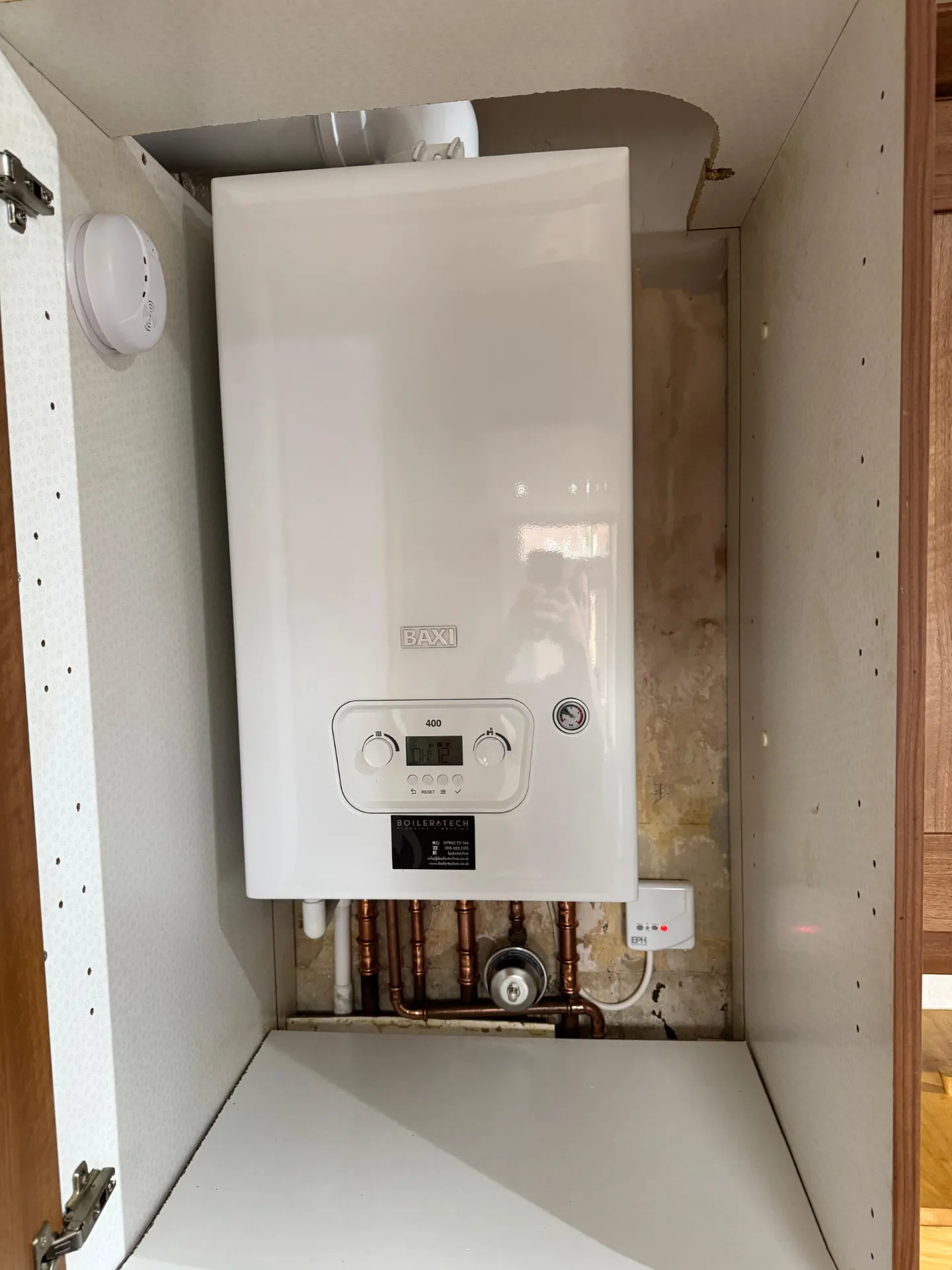 Baxi 400 combi boiler fitted neatly inside a kitchen cupboard with copper pipework